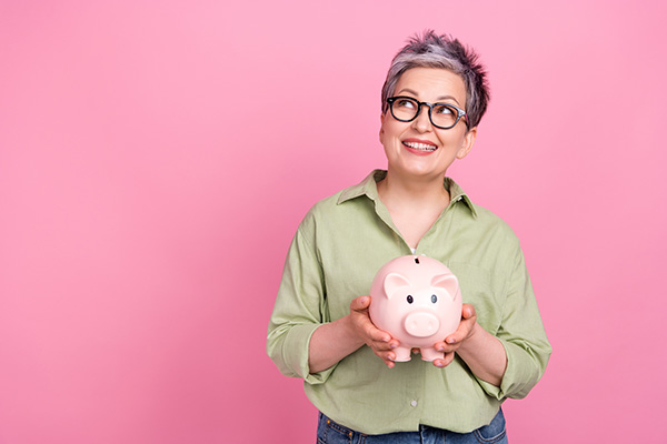 A lady holds a piggy bank, thinking about her money.